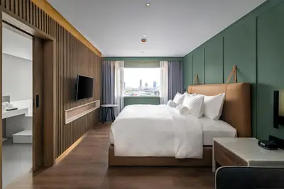a hotel room with a large bed and a window at Maison Hotel Bangkok in Bangkok