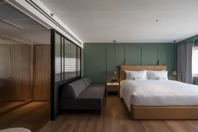 a bedroom with a bed and a chair at Maison Hotel Bangkok in Bangkok