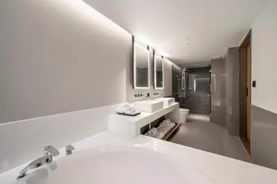 a white bathroom with two sinks and a tub at Maison Hotel Bangkok in Bangkok