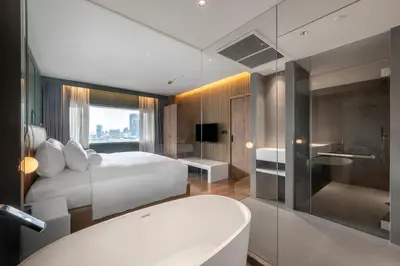 a bedroom with a bed and a bathroom with a tub at Maison Hotel Bangkok in Bangkok
