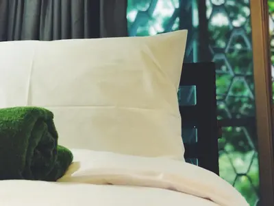 a pillow sitting on top of a bed next to a window at Victory Park Hostel in Bangkok