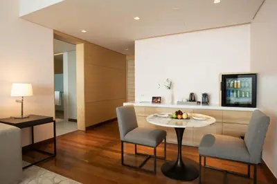 a living room with a table and chairs and a kitchen at Avani Plus Riverside Bangkok Hotel in Bangkok