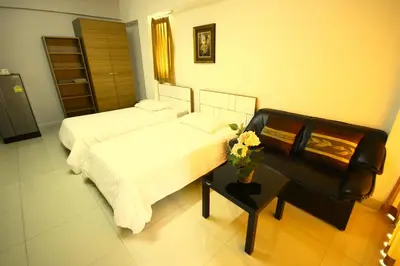 a bedroom with two beds and a table with flowers at At Home Phetkasem in Bangkok