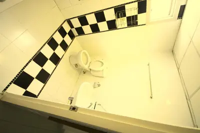 a bathroom with a toilet and a checkered wall at At Home Phetkasem in Bangkok