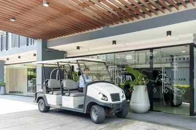 a man driving a golf cart in front of a building at Chiva Bangkok Hotel in Bangkok