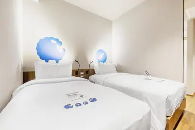 two beds in a room with a cloud on the wall at Kokotel Bangkok Surawong in Bangkok
