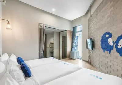 a bedroom with two beds and a brick wall at Kokotel Bangkok Surawong in Bangkok