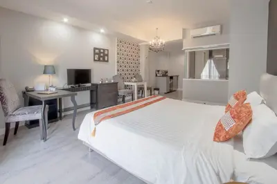 a bedroom with a large white bed and a desk at The Star of Sathorn in Bangkok