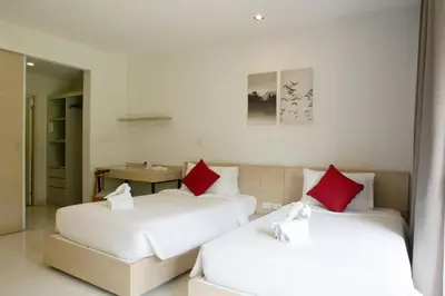 two beds with red pillows in a room at The Silver Palm Wellness Resort in Bangkok