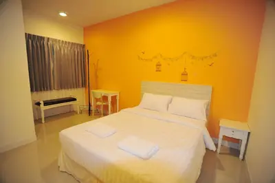a bedroom with a white bed with an orange wall at The Garden Living in Bangkok