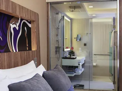 a bathroom with a bed and a shower and a sink at Novotel Bangkok Sukhumvit 20 in Bangkok