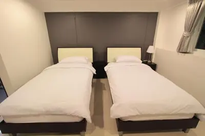 two beds in a room with white sheets at Napaville Huai Khwang in Bangkok