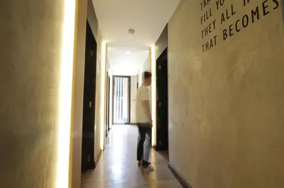 a person walking down a hallway with writing on the wall at Cazz Hostel in Bangkok