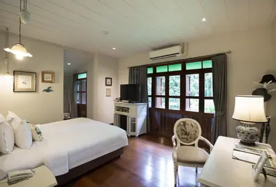 a bedroom with a bed and a desk and a television at The Raweekanlaya Bangkok Wellness Cuisine Resort in Bangkok