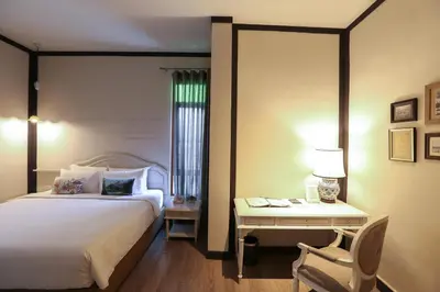 a bedroom with a bed and a desk with a chair at The Raweekanlaya Bangkok Wellness Cuisine Resort in Bangkok