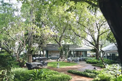 a building with tables and chairs in a garden at The Raweekanlaya Bangkok Wellness Cuisine Resort in Bangkok