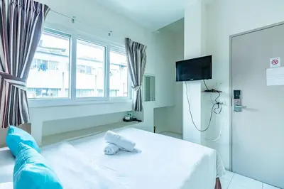 a bedroom with a white bed and a television at Sleep Dee Hostel in Bangkok