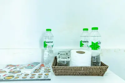 a basket of water and toilet paper and a remote control at Sleep Dee Hostel in Bangkok