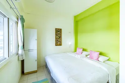 a bedroom with a large white bed with pink pillows at Sleep Dee Hostel in Bangkok