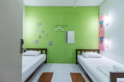 two beds in a room with green walls at Sleep Dee Hostel in Bangkok