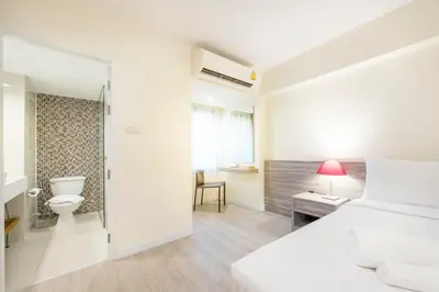 a bedroom with a white bed and a bathroom at Le Tada Residence in Bangkok