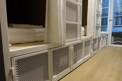 a room with white bunk beds with a window at On the Bed Hostel in Bangkok
