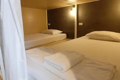 two beds in a small room with a mirror at On the Bed Hostel in Bangkok