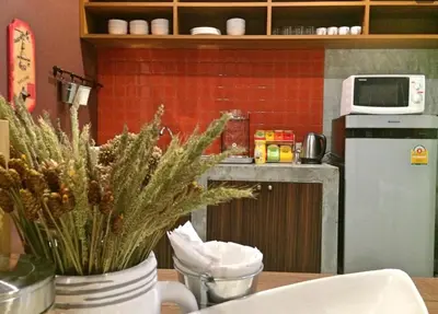 a kitchen with a table with a plant in a vase at Yoo Yen Pen Sook in Bangkok