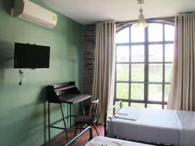a bedroom with a bed and a desk and a window at J No.14 in Bangkok