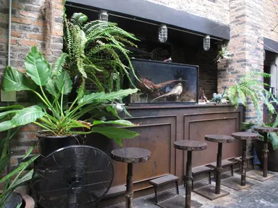 a patio with a bar with stools and plants at J No.14 in Bangkok