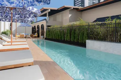 a swimming pool with chairs and an umbrella next to a building at Metropole, Bangkok, a Tribute Portfolio Hotel by Marriott in Bangkok