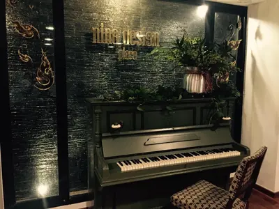 a piano in a room with a black brick wall at Nine Design Place in Bangkok