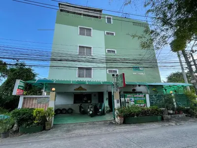 a green building with a motorcycle parked in front of it at Gedkanok Apartment in Bangkok