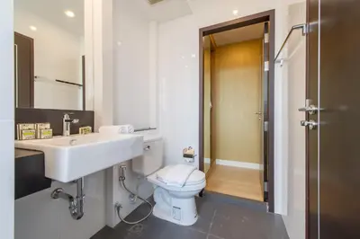 a white bathroom with a sink and a toilet at Zenniq in Bangkok