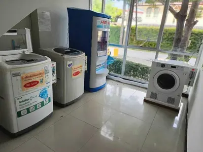 a laundry room with a washing machine and a window at Collection O The Bangkok Cha Cha Suite in Bangkok