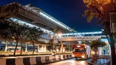a bus driving under an overpass with a train on it at Collection O The Bangkok Cha Cha Suite in Bangkok
