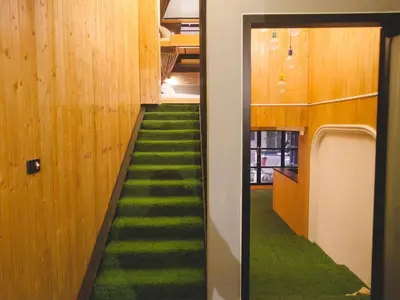 a hallway with green carpet and a stairway at Double Five in Bangkok