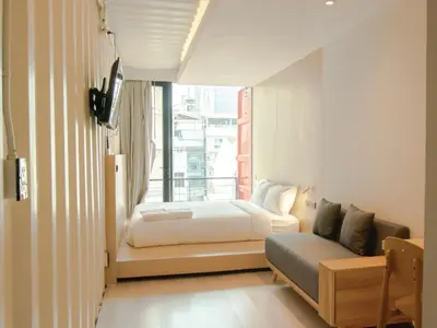 a bedroom with a bed and a couch and a window at Sleep Box Hotel Sukhumvit 22 in Bangkok