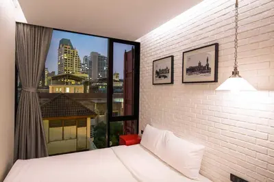 a bedroom with a white bed and a large window at Sleep Box Hotel Sukhumvit 22 in Bangkok