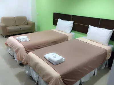 two beds in a hotel room with a chair at Diamond Bangkok Apartment in Bangkok