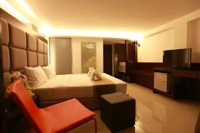 a hotel room with a bed and a red chair at The Bangkok Major Suite in Bangkok