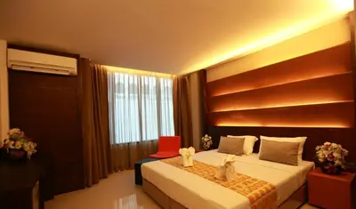 a bedroom with a bed with a red chair and a window at The Bangkok Major Suite in Bangkok