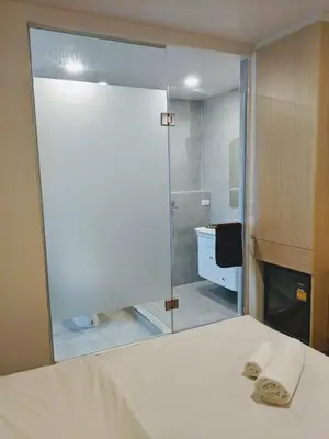 a bathroom with a shower and a bed and a mirror at Good One Poshtel & Cafe Bar in Bangkok