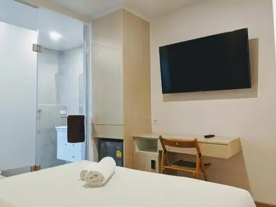 a room with a bed and a tv on the wall at Good One Poshtel & Cafe Bar in Bangkok
