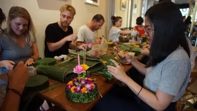 a group of people sitting around a table with a cake at Good One Poshtel & Cafe Bar in Bangkok