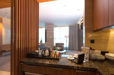 a kitchen with a counter and a living room at Lancaster Bangkok in Bangkok