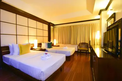 a hotel room with two beds and a television at Grand Business Inn in Bangkok