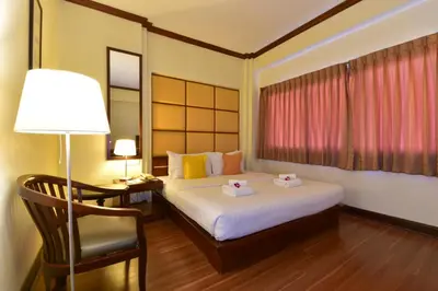 a bedroom with a bed and a lamp and a chair at Grand Business Inn in Bangkok