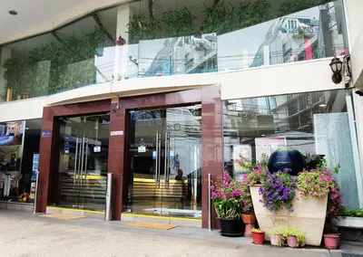 a glass building with flowers in front of it at Grand Business Inn in Bangkok