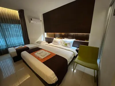 a hotel room with two beds and a chair at Collection O The Bangkok Airport Link Suite in Bangkok